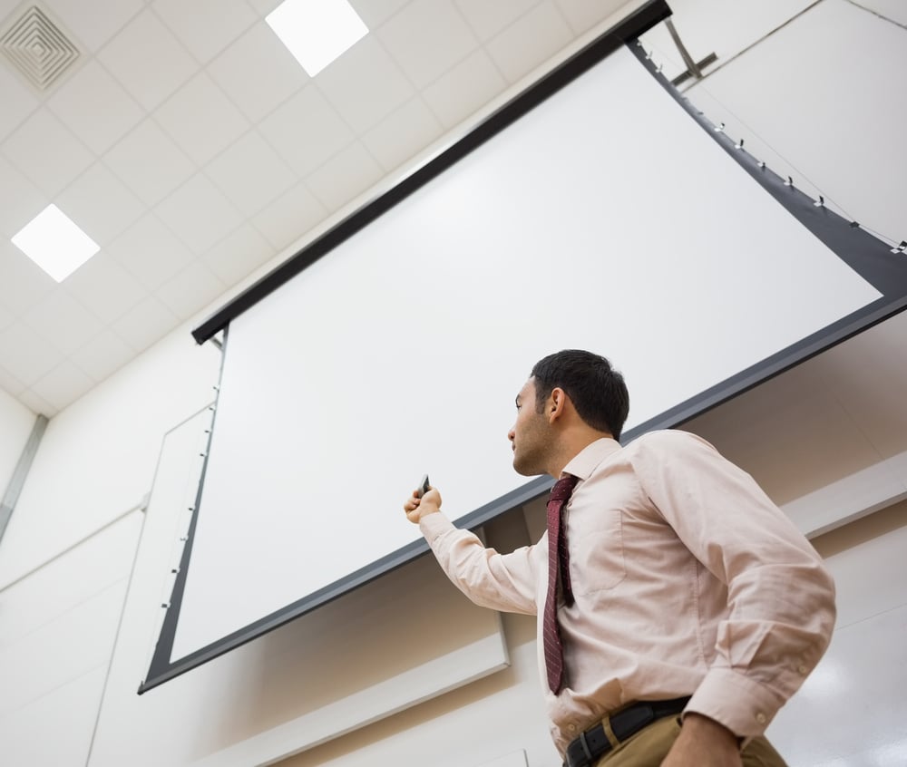 Low angle view of an elegant male teacher with projection screen in the lecture hall Low angle view of an elegant male teacher with projection screen in the lecture hall
