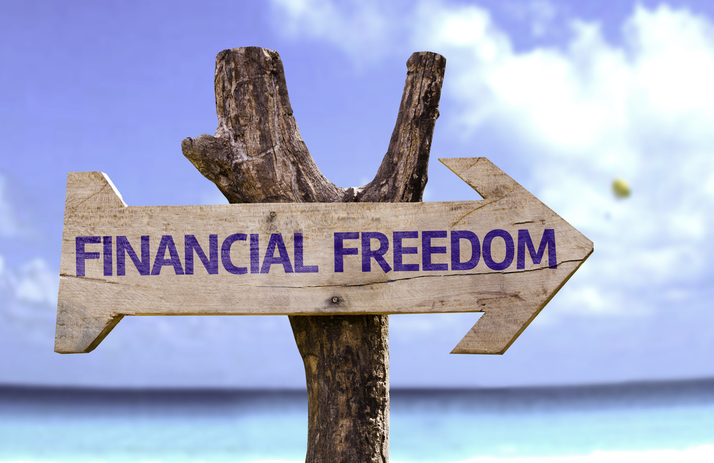 Financial Freedom wooden sign with a beach on background Financial Freedom wooden sign with a beach on background